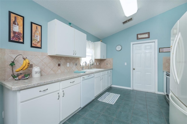 kitchen featuring light countertops, vaulted ceiling, visible vents, white appliances, and decorative backsplash