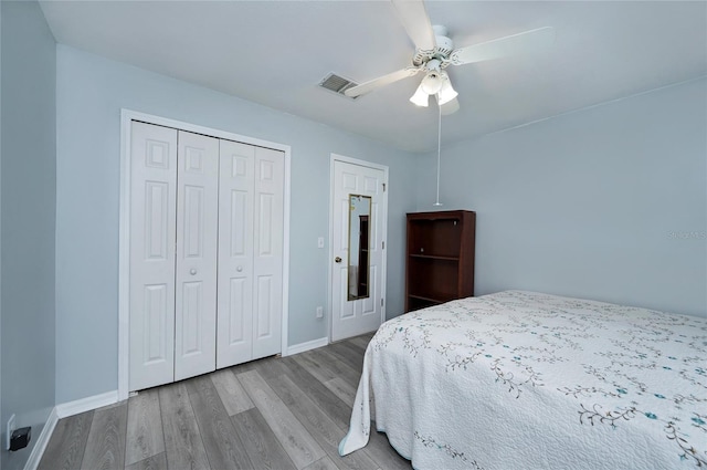 bedroom featuring visible vents, baseboards, a closet, a ceiling fan, and wood finished floors