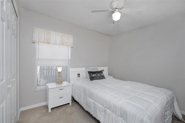 bedroom with light carpet, multiple windows, baseboards, and a textured ceiling
