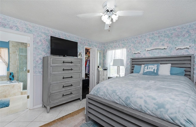 bedroom featuring a closet, wallpapered walls, light tile patterned floors, connected bathroom, and a walk in closet