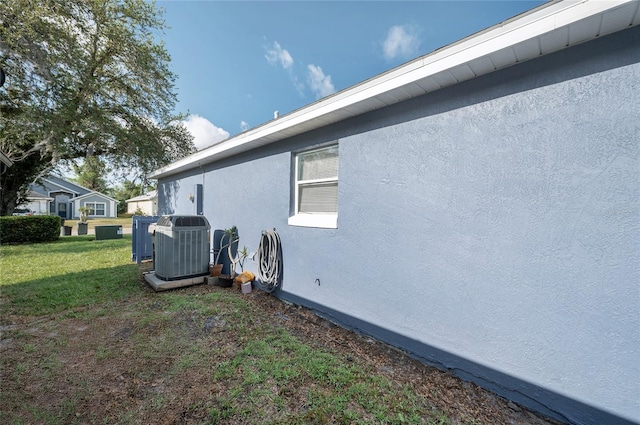 view of home's exterior with cooling unit, stucco siding, and a lawn