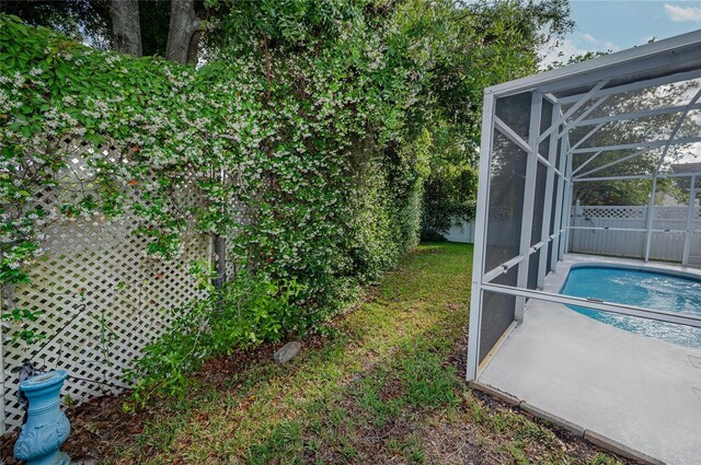 view of yard featuring a fenced in pool and glass enclosure