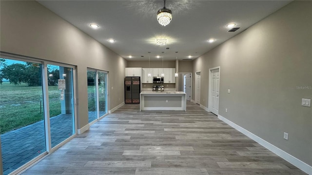 7908 Pine Glen Rd, Sebring, FL 33876 - kitchen with fridge with ice dispenser, stainless steel microwave, light countertops, light wood-style flooring, and white cabinets