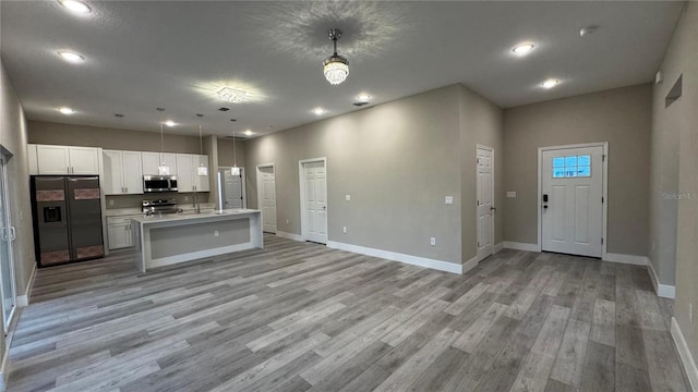 7908 Pine Glen Rd, Sebring, FL 33876 - kitchen with appliances with stainless steel finishes, open floor plan, light wood-style flooring, white cabinets, and light countertops