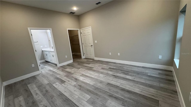 7908 Pine Glen Rd, Sebring, FL 33876 - unfurnished bedroom featuring a walk in closet, wood finished floors, ensuite bath, and a closet