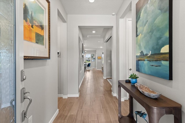 hallway with wood finished floors, visible vents, and baseboards