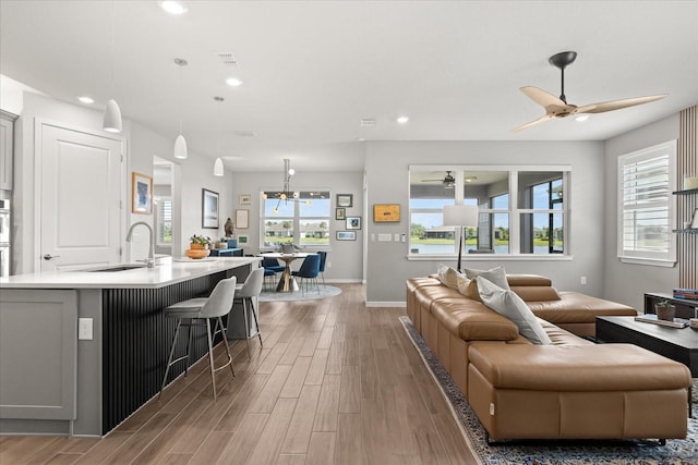 living room with light wood-type flooring, a ceiling fan, and recessed lighting