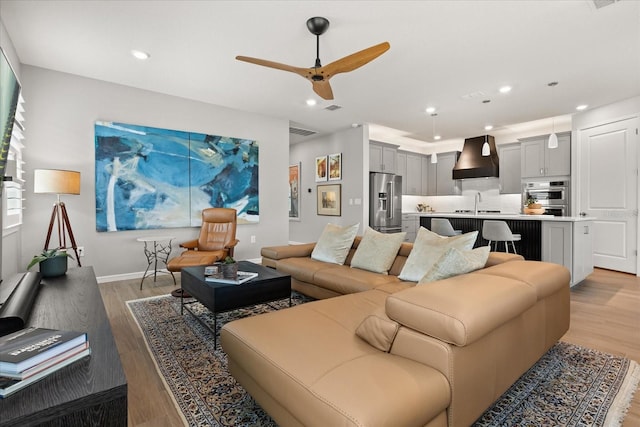 living room featuring light wood-type flooring, visible vents, baseboards, ceiling fan, and recessed lighting