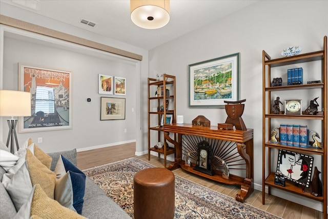 living area with baseboards, visible vents, and wood finished floors