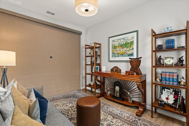 living area featuring visible vents, wood finished floors, and baseboards