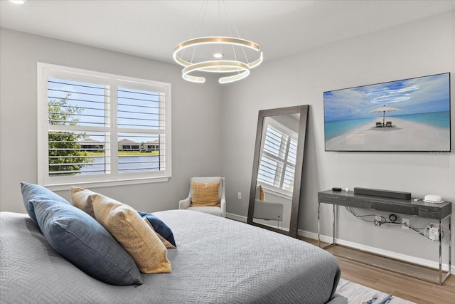 bedroom with baseboards, multiple windows, an inviting chandelier, and wood finished floors