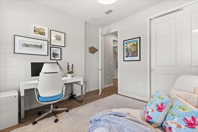 home office with visible vents, wood finished floors, and baseboards