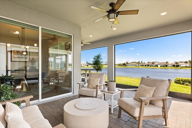 sunroom featuring plenty of natural light, a water view, and ceiling fan