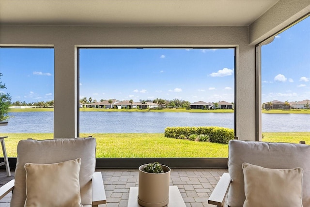 sunroom featuring a water view and a residential view