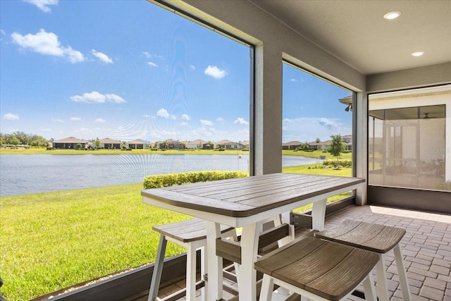 sunroom / solarium featuring a water view and a residential view