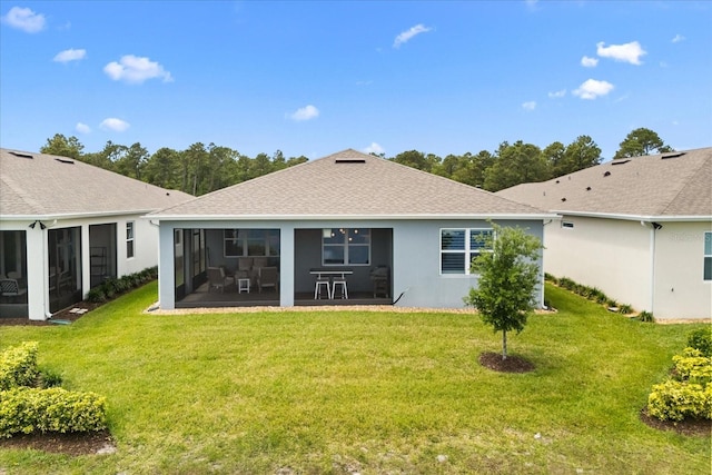 back of property with a lawn, a sunroom, and a shingled roof
