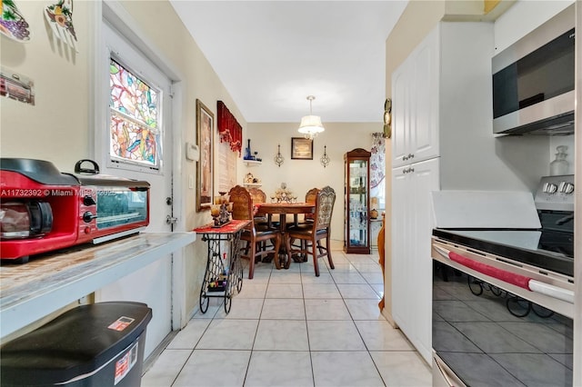 kitchen featuring light tile patterned floors, white cabinets, decorative light fixtures, light countertops, and appliances with stainless steel finishes