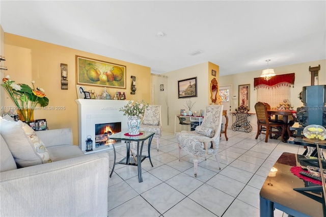 living area featuring a glass covered fireplace, light tile patterned floors, and visible vents