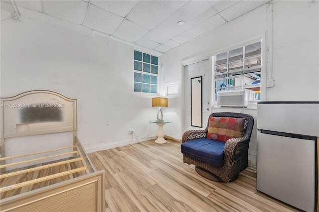 sitting room with cooling unit, a paneled ceiling, wood finished floors, and baseboards
