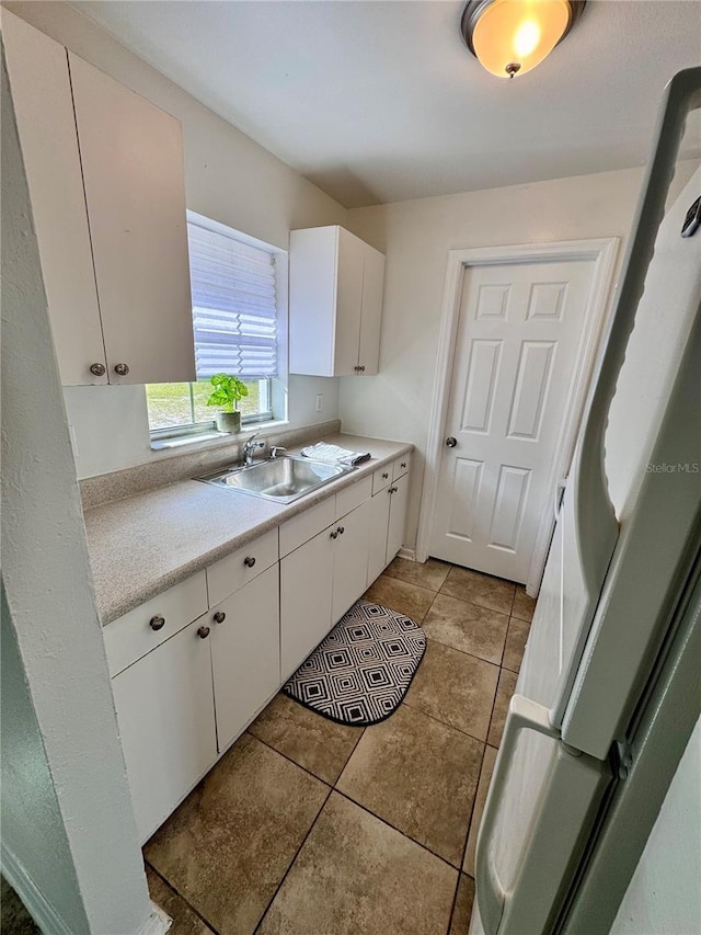 kitchen with light countertops, white cabinets, light tile patterned floors, and a sink