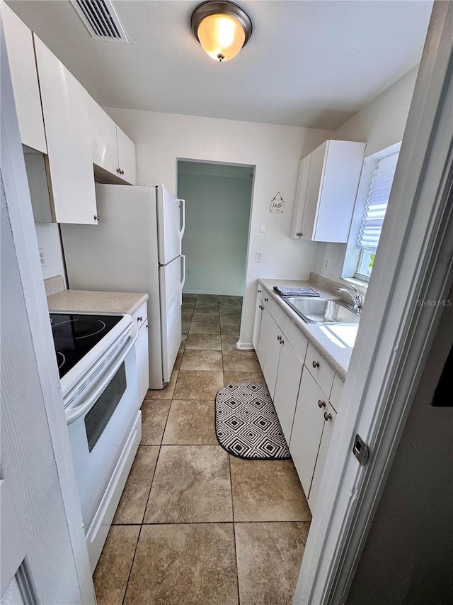 kitchen featuring light countertops, visible vents, a sink, white range with electric cooktop, and white cabinetry