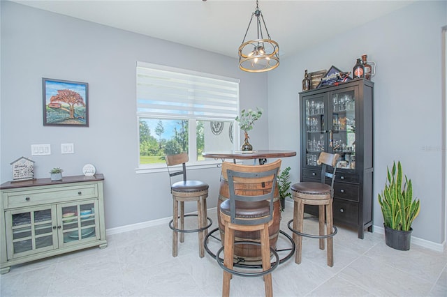 tiled dining room featuring a chandelier and baseboards