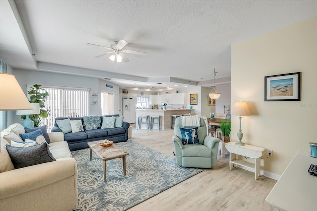 5300 S Atlantic Ave Unit 2-501, New Smyrna Beach, FL 32169 - living area featuring light wood-type flooring, a healthy amount of sunlight, a ceiling fan, and a textured ceiling