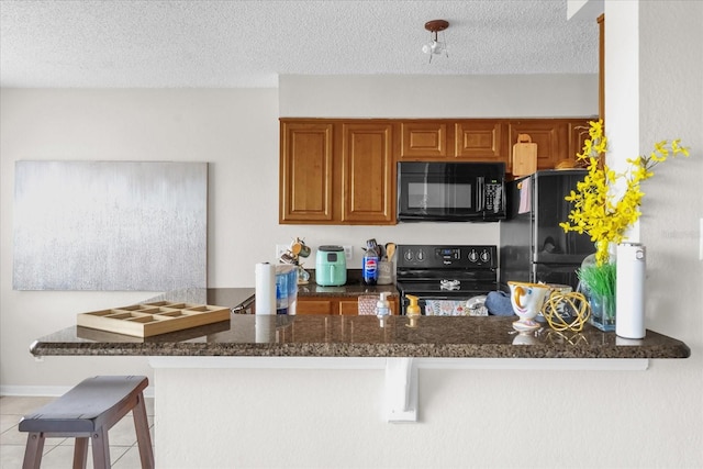 1065 S Hiawassee Rd Unit 1436, Orlando, FL 32835 - kitchen featuring brown cabinets, a textured ceiling, a peninsula, light tile patterned floors, and black appliances