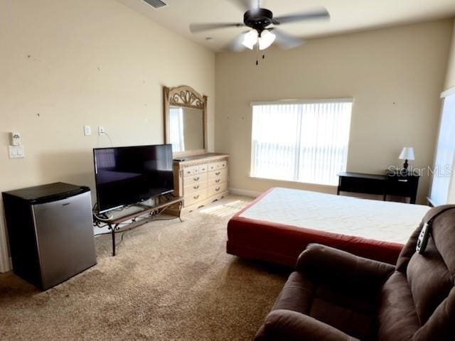 carpeted bedroom featuring freestanding refrigerator, ceiling fan, and visible vents