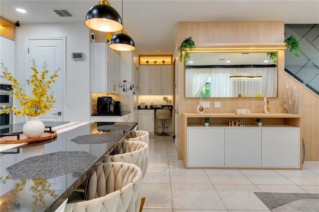 8109 Ludington Cir, Orlando, FL 32836 - kitchen with decorative light fixtures, tasteful backsplash, white cabinetry, and visible vents