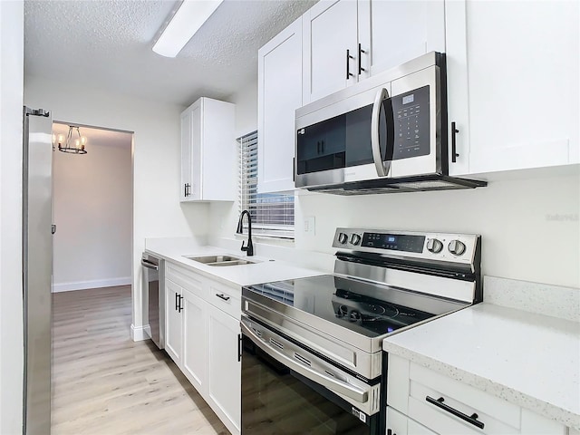 7400 Mitchell Ranch Rd, New Port Richey, FL 34655 - kitchen featuring appliances with stainless steel finishes, a sink, light wood-style floors, white cabinets, and a textured ceiling