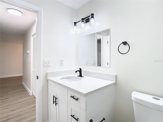 7400 Mitchell Ranch Rd, New Port Richey, FL 34655 - bathroom with toilet, vanity, wood finished floors, and baseboards