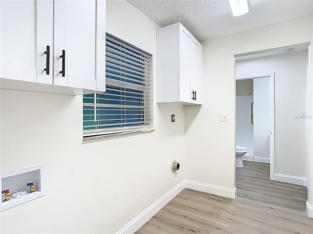 7400 Mitchell Ranch Rd, New Port Richey, FL 34655 - laundry area featuring light wood-style floors, baseboards, cabinet space, washer hookup, and a textured ceiling