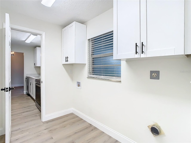 7400 Mitchell Ranch Rd, New Port Richey, FL 34655 - washroom featuring light wood-style flooring, hookup for a washing machine, hookup for an electric dryer, baseboards, and a textured ceiling