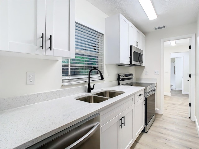 7400 Mitchell Ranch Rd, New Port Richey, FL 34655 - kitchen featuring stainless steel appliances, a sink, white cabinets, and light wood-style floors