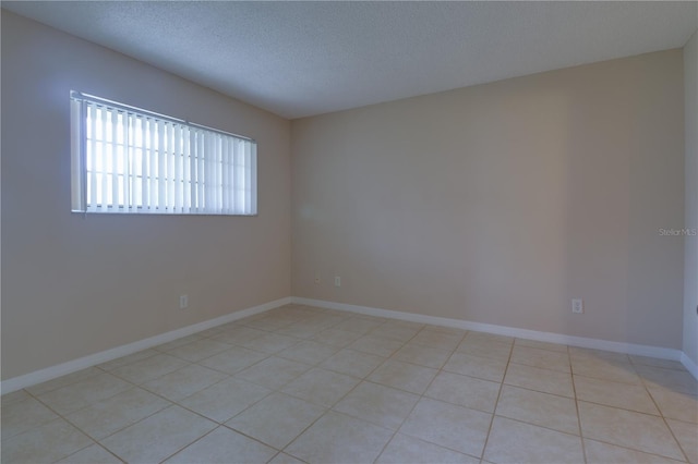 unfurnished room featuring light tile patterned floors, baseboards, and a textured ceiling