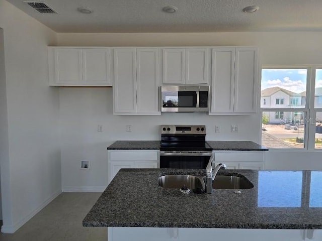 2976 Embark Trl, Saint Cloud, FL 34771 - kitchen with stainless steel appliances, a sink, white cabinets, and dark stone counters