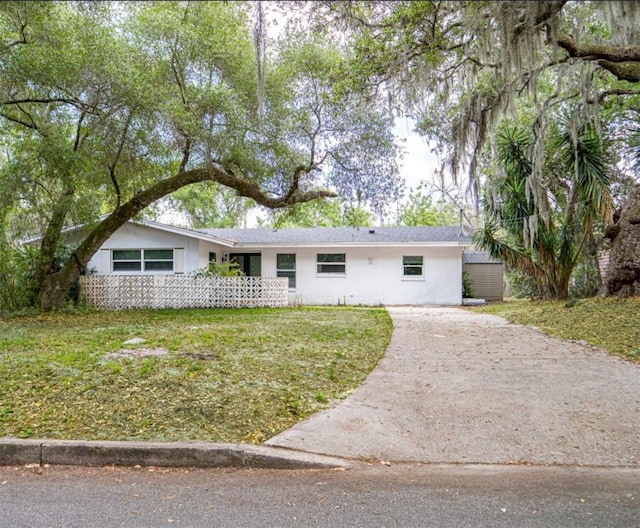 ranch-style house with concrete driveway, stucco siding, and a front lawn