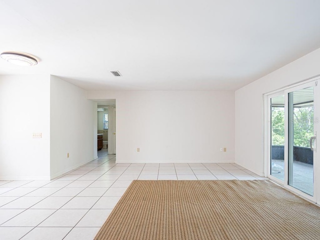 unfurnished room featuring light tile patterned floors, visible vents, and baseboards