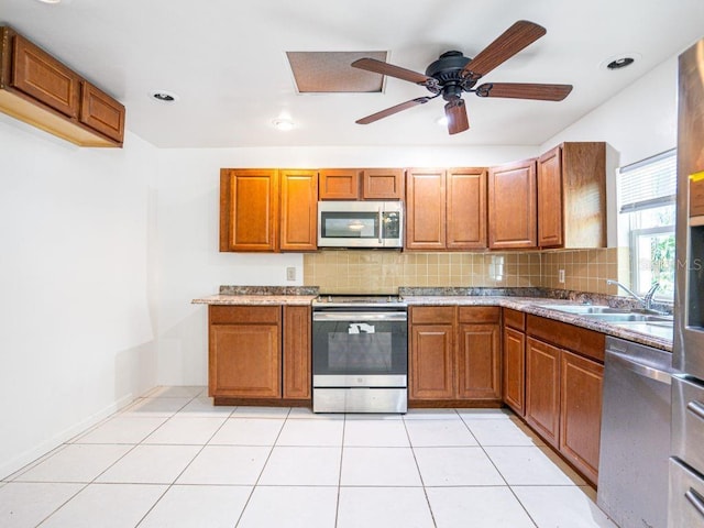 kitchen with a sink, decorative backsplash, appliances with stainless steel finishes, and brown cabinets