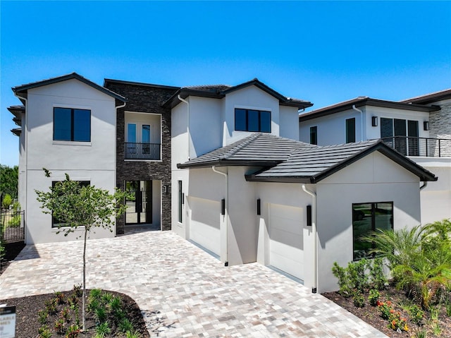 1080 E Jack Nicklaus Ct, Kissimmee, FL 34747 - view of front of house featuring stucco siding, decorative driveway, a tile roof, a balcony, and an attached garage
