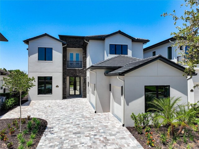 1080 E Jack Nicklaus Ct, Kissimmee, FL 34747 - view of front of property with stucco siding, decorative driveway, stone siding, a garage, and a tile roof