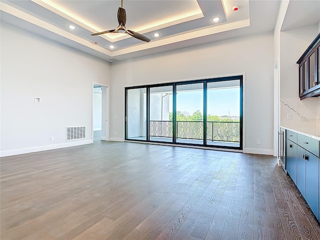 1080 E Jack Nicklaus Ct, Kissimmee, FL 34747 - unfurnished living room with a tray ceiling, baseboards, a ceiling fan, wood finished floors, and a towering ceiling