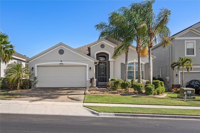 mediterranean / spanish house featuring a front lawn, a garage, driveway, and stucco siding