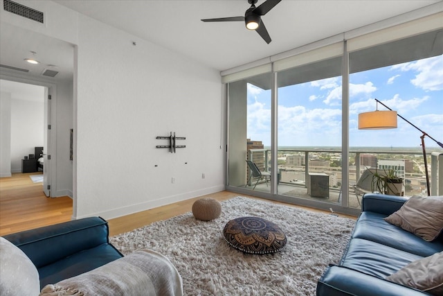 living room featuring floor to ceiling windows, ceiling fan, wood finished floors, and baseboards