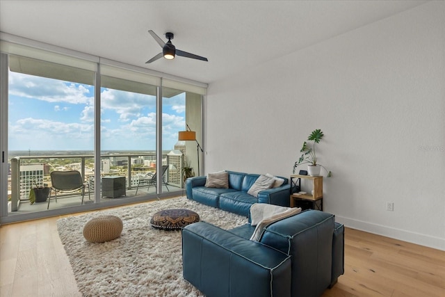 living room with floor to ceiling windows, ceiling fan, wood finished floors, and baseboards