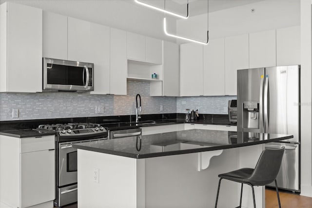 kitchen with appliances with stainless steel finishes, a center island, white cabinets, and tasteful backsplash