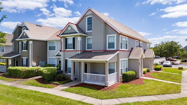 multi unit property with a residential view, a front lawn, covered porch, and stucco siding