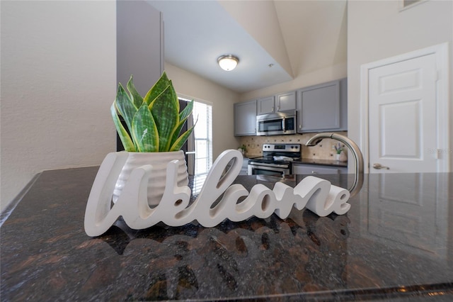 details with gray cabinets, backsplash, and appliances with stainless steel finishes