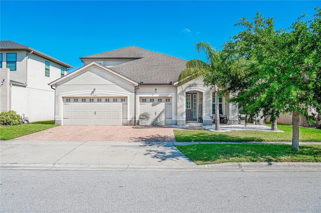 3041 Cardillino Way, Kissimmee, FL 34741 - view of front of house with roof with shingles, stucco siding, decorative driveway, an attached garage, and a front lawn